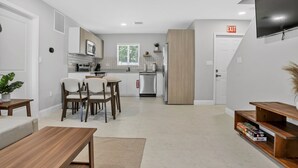 A modern kitchen with white cabinets, a built-in oven, and a window with blinds.