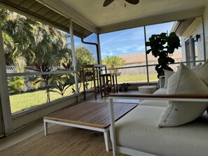 Relax in this serene sunroom with a garden view, featuring a sofa and bench.