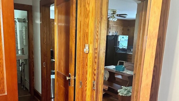 Ein Holzboden-Flur, durch eine offene Tür ist eine Küche zu sehen.