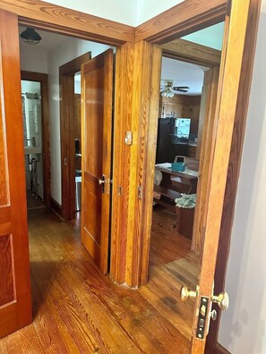 A wooden interior hallway with a kitchen area visible through an open door. - ESVA Down by the Sea & Pet Friendly (Onancock)