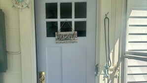 Eine weiße Haustür mit kleinem Fenster und einem Schild, auf dem steht: "der Strand ist mein glücklicher Ort".