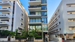 A multi-story residential building with balconies, a gated entrance, and a small parking area.