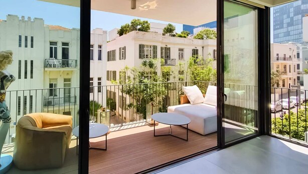 A balcony with a sofa, a small table, and a chair.
