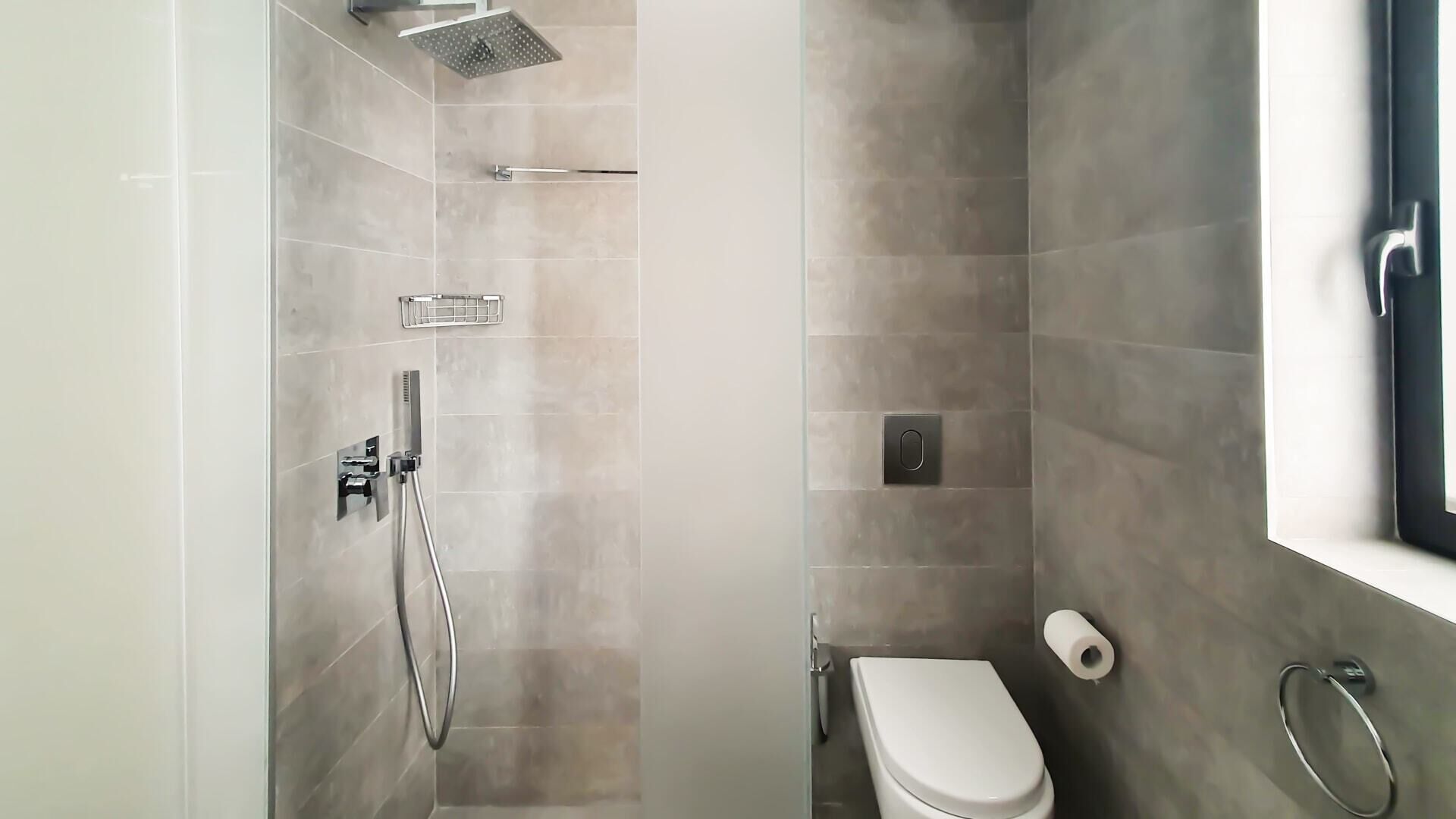 Ein modernes Badezimmer mit Dusche, Toilette und Toilettenpapierhalter.