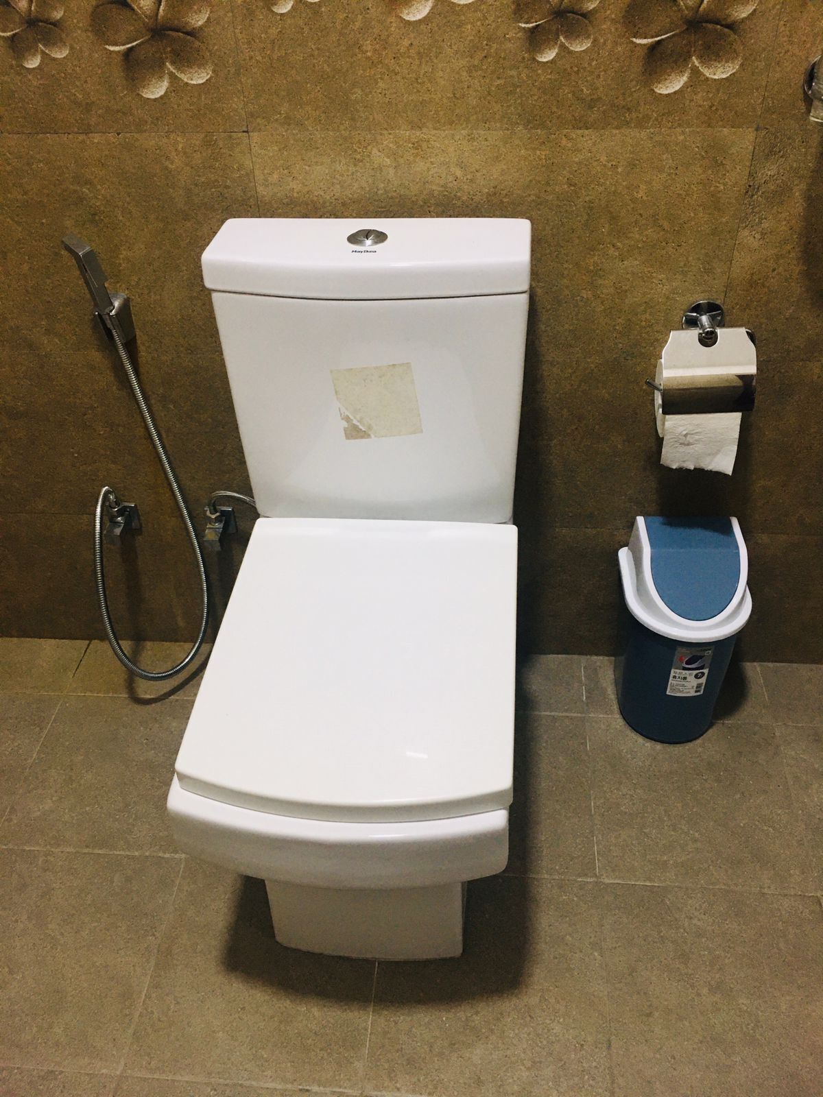 Un inodoro con dispensador de toallas de papel y bidé.