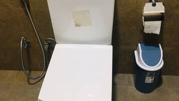 Un inodoro con dispensador de toallas de papel y bidé.