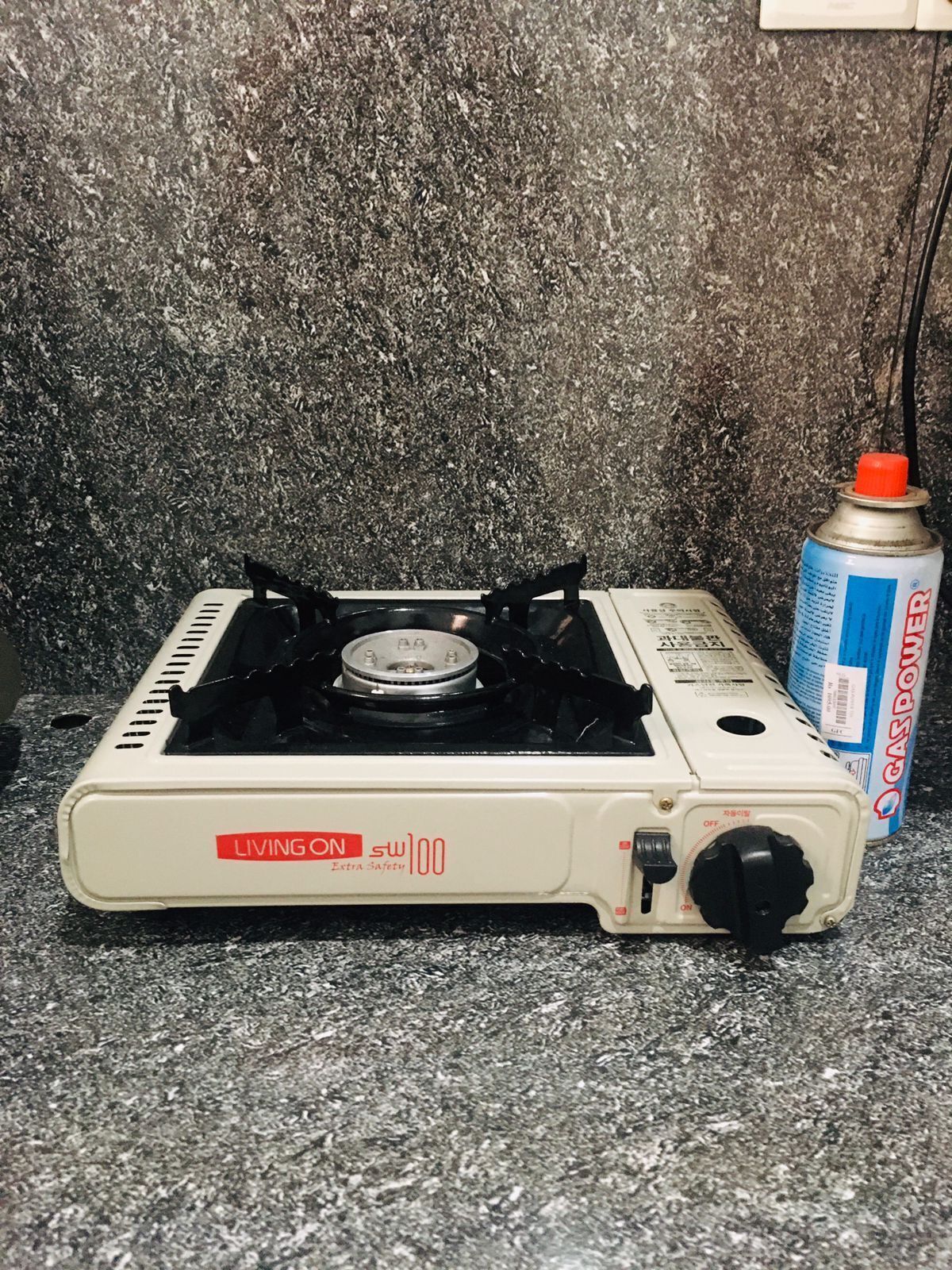 A portable gas stove with a can of gas-powered cleaner next to it.