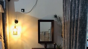 Quarto com mesa consola de madeira, espelho fixado na parede, mesinha de cabeceira e ar condicionado instalado na parede.