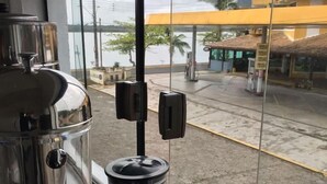 A kitchen with a coffee machine and a blender, a window with a view of a gas station and palm trees. - Cananéia (Cananeia)