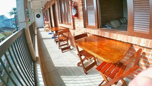 A covered outdoor seating area with brick walls, wooden tables and chairs, and a fire extinguisher mounted on the wall. - Cananéia (Cananeia)