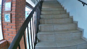 A staircase with a brick column and metal railing, leading to an upper floor. - Cananéia (Cananeia)