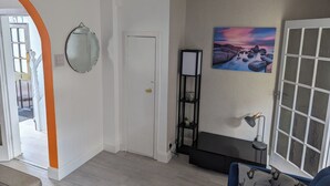 A living room with a door, a mirror, a shelf with plants, a painting, and a window with a view. - Fantastic Location to Ebrington Sq and City Centre (Londonderry)