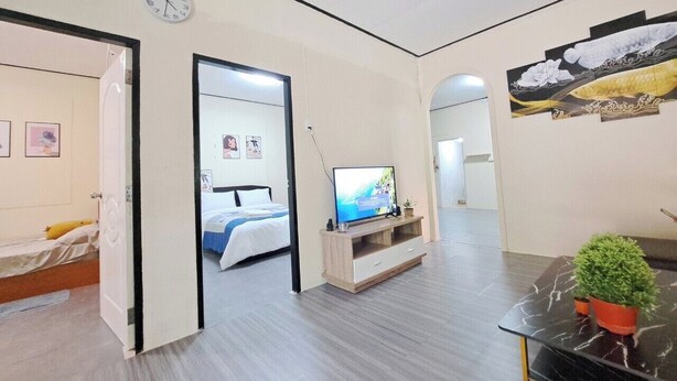 A modern hotel room with a bed, a TV, a small table with a plant, and a wall clock. - Getaway near Patong Beach, shops and restaurants. Homey, private, and memorable. (Tambon Patong)