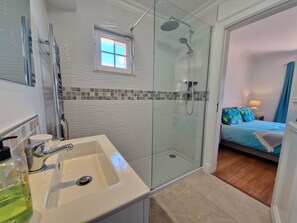Ein Badezimmer mit Duschkabine, Waschbecken und kleinem Fenster.