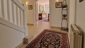 A hallway with a patterned rug, a radiator, and framed pictures on the walls.