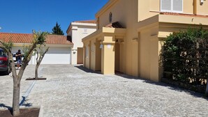 A paved street with buildings, a clear blue sky, and a few trees.