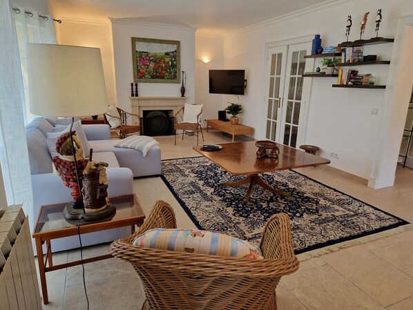 A living room with a sofa, a coffee table, a fireplace, and a TV mounted on the wall.