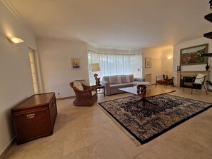 A living room with a sofa, armchairs, a coffee table, a fireplace, and a rug.