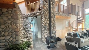 A spacious living area with a stone fireplace, a wooden staircase, and a cozy seating area.
