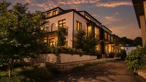 A modern two-story house with a balcony, a driveway, and a well-maintained garden.