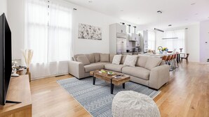 A modern living room with a sectional sofa, a coffee table, and a TV on a wooden stand.