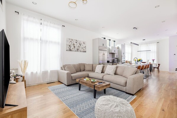 Una sala de estar moderna con un sofá modular, una mesa de centro y un televisor sobre un mueble de madera.