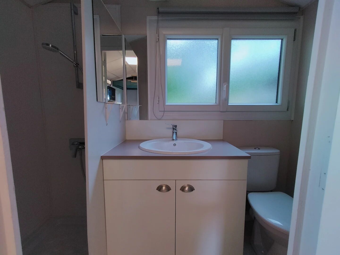A small bathroom with a white sink, a mirror, and a toilet.