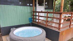 A hot tub with a wooden deck and a green wall. - La Tiny de Papy (Attignat)