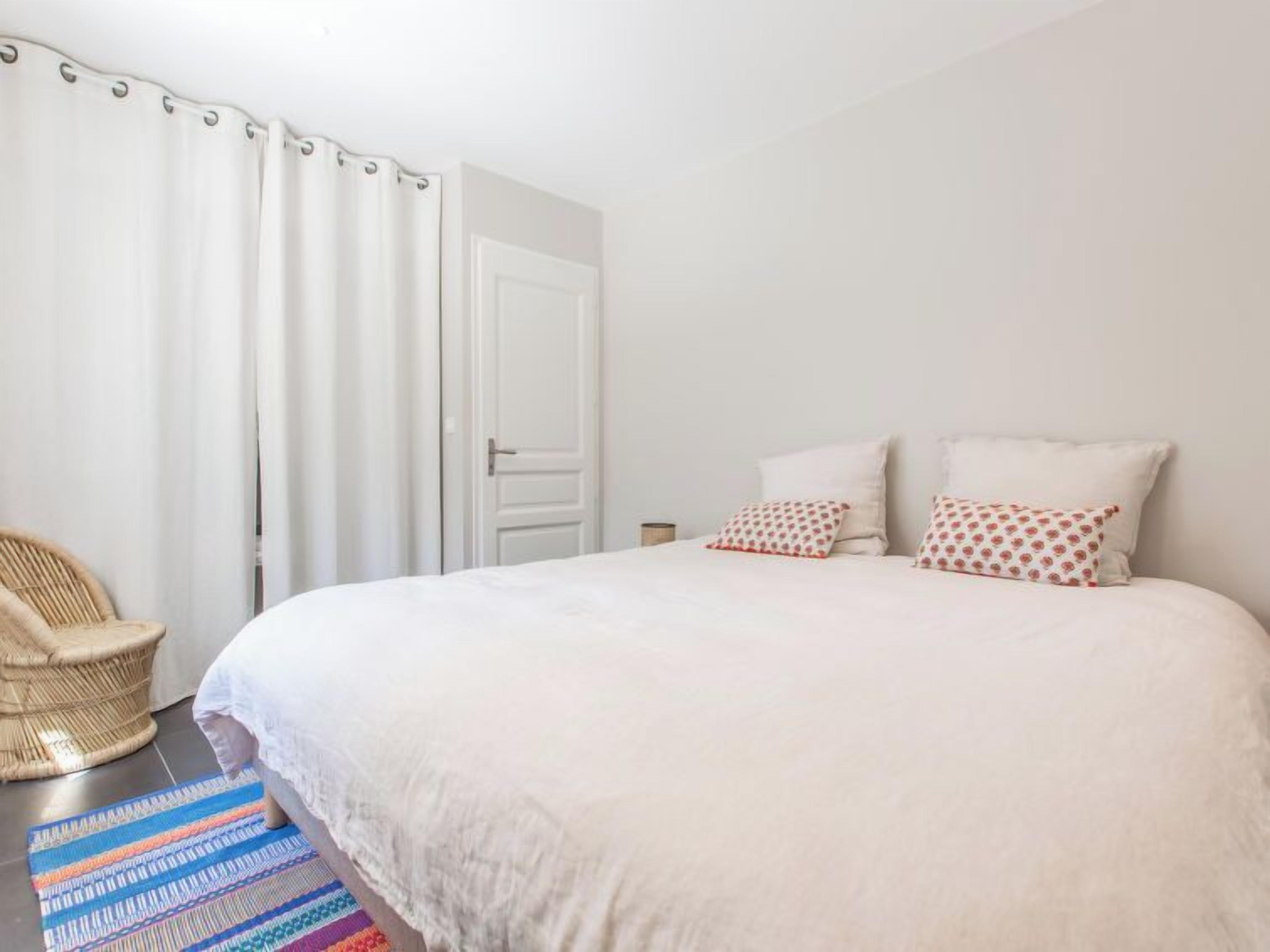Un dormitorio con una cama grande, una silla y una alfombra colorida.