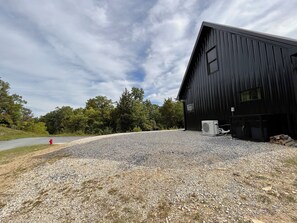 Un camino de grava conduce a un edificio de metal negro con un letrero que dice 'New Barn'.