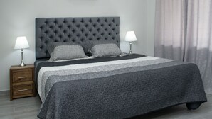 A neatly made bed with a tufted headboard, two bedside lamps, and a grey patterned bedspread. - CASA TOTALMENTE RENOVADA CON TODA LAS COMODIDADES Y CARACTERISTICAS DE ALTA GAMA (Cali)