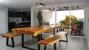 A modern kitchen with dark cabinets and a wooden dining table with benches. - CASA TOTALMENTE RENOVADA CON TODA LAS COMODIDADES Y CARACTERISTICAS DE ALTA GAMA (Cali)