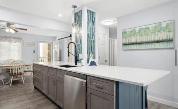 A modern kitchen with a large island, stainless steel appliances, and a dining area with a table and chairs.