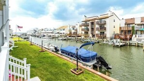 Un puerto deportivo con barcos amarrados, una zona verde y edificios residenciales con balcones.