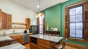 A kitchen with wooden cabinets, a stainless steel refrigerator, a marble countertop, and a large window with a view. - The Selbert - In the Heart of The Bourbon Trail! (Frankfort)