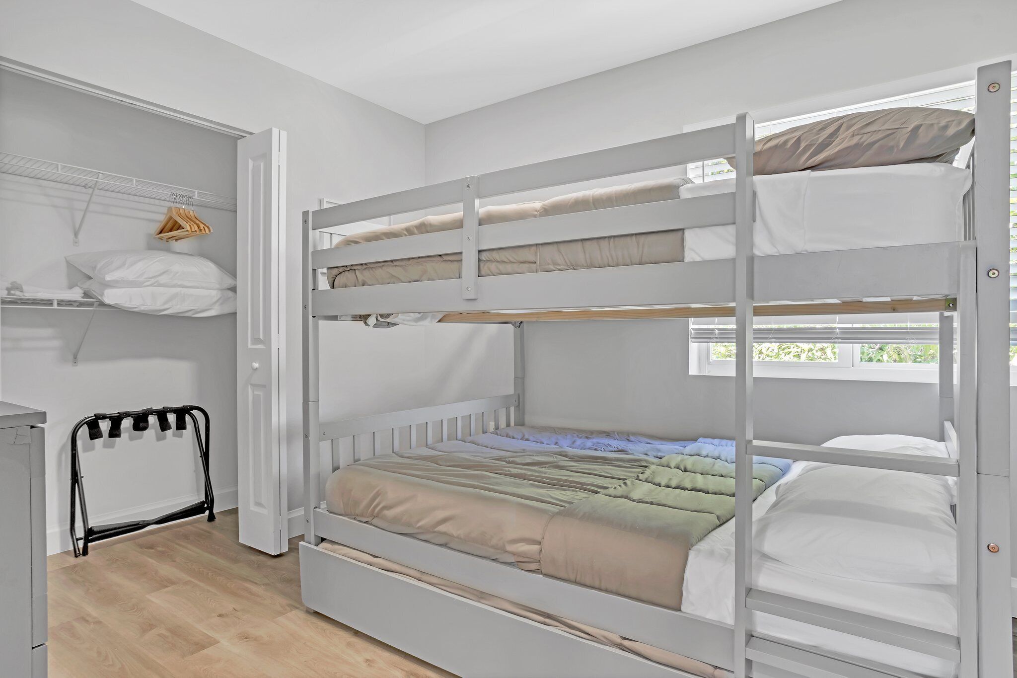 Habitación con literas, un armario, un tendedero y un escritorio pequeño.