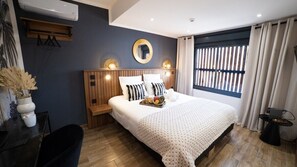 A modern bedroom with a large bed, wooden headboard, bedside tables, a desk, and a window with curtains. - 10 Rue Du Four à Chaux (Saint-Denis)