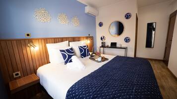 Una cama bien hecha con colcha azul, una mesita de noche con lámpara y un aire acondicionado de pared.