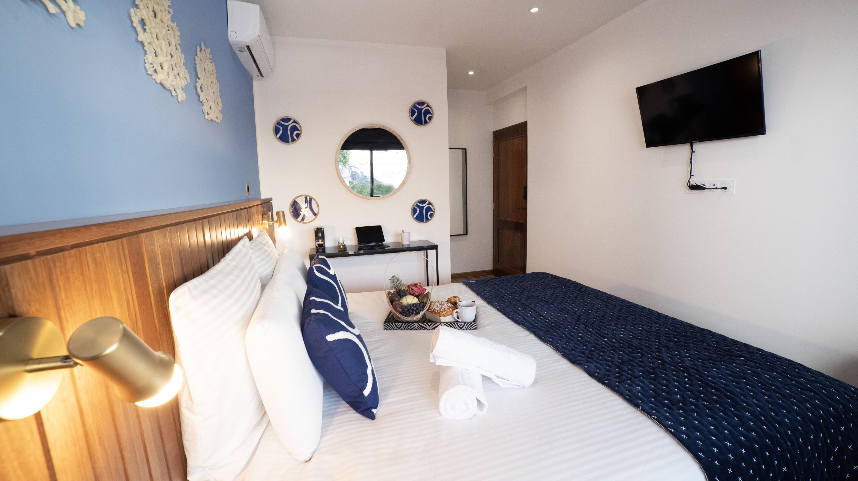 Habitación de hotel con cama, mesita de noche, lámpara, televisión y aire acondicionado instalado en la pared.