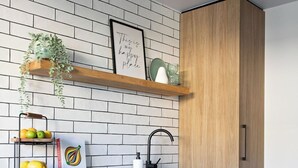 A modern kitchen with white cabinetry, a black dishwasher, and a wooden cabinet. - By the Bay Batehaven - King, Queen, 2 x Singles. Opposite Corrigans Beach & Park (Batehaven)