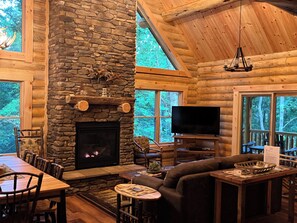 L’intérieur d’une cabane en rondins, avec une cheminée en pierre, des meubles en bois et un téléviseur.