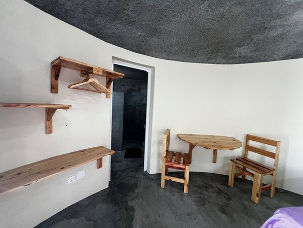 A room with a curved ceiling, a wooden bench, a small table, and two chairs.