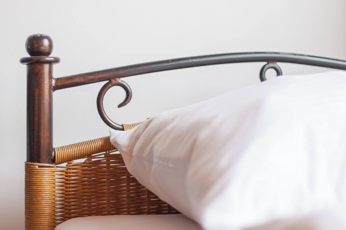 A bed with a wooden headboard and a white pillow.