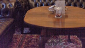 A room with a leather sofa, a round wooden table, and a hanging light fixture. - Union Hotel by TM (Dortmund)