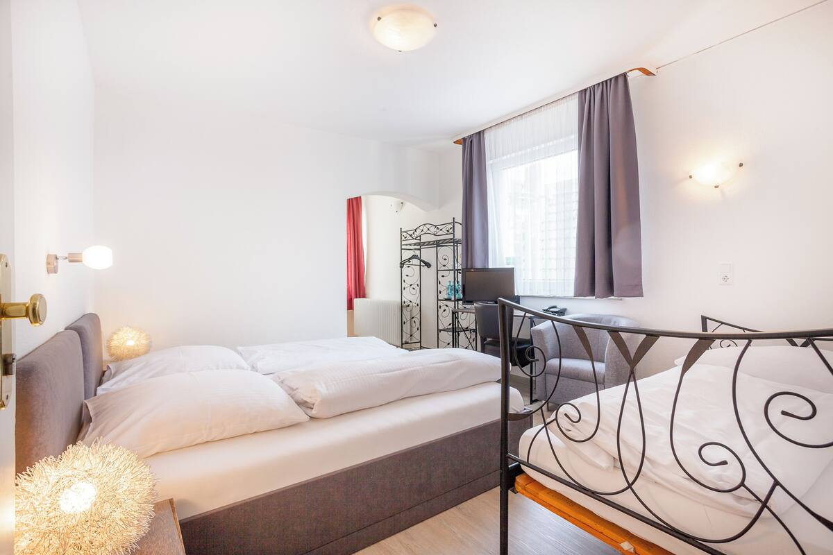A modern hotel room with a single bed, a desk, and a chair.