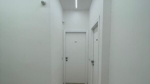 A narrow hallway with white walls and a tiled floor, leading to a door at the end. - B&B Corso 219 (Montesilvano)