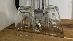 Una cafetera francesa con dos jarrones de vidrio sobre una superficie de madera.