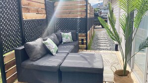 Un patio con un sofá modular, una planta en maceta y una valla de madera.