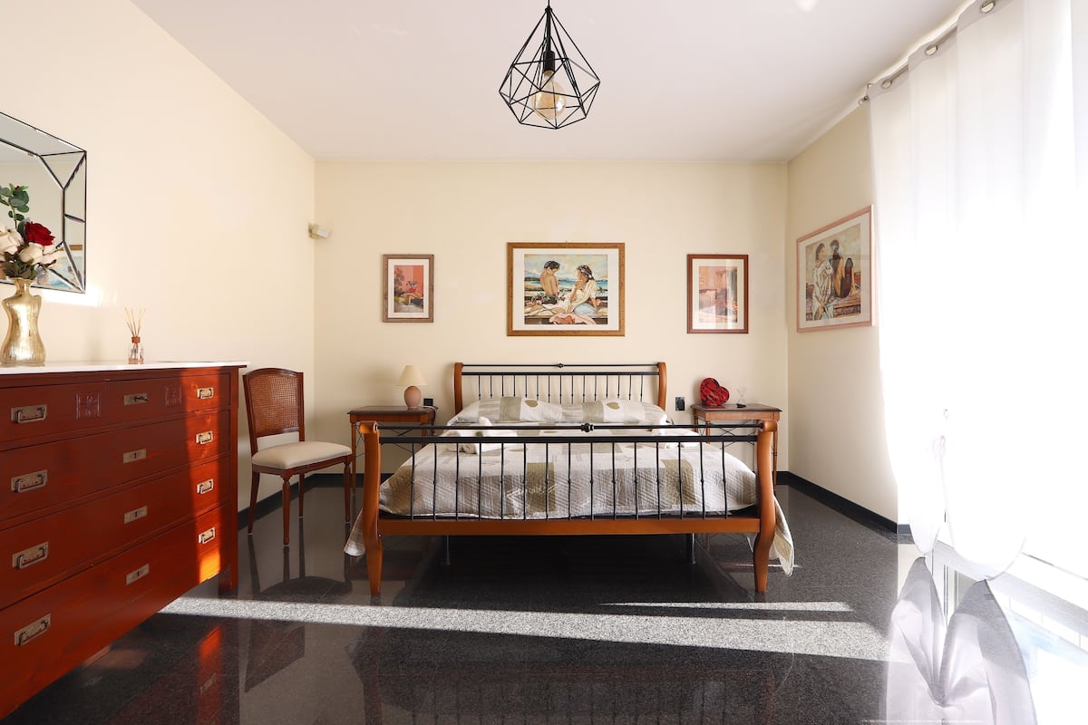 Un dormitorio con una cama de madera, un aparador, una silla y un espejo.