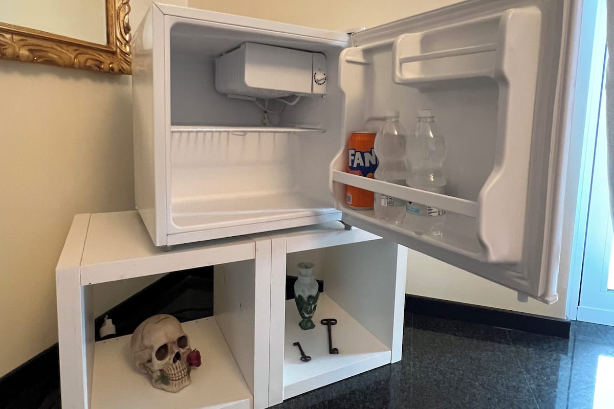 Un mini refrigerador con un estante inferior que contiene una calavera y llaves.